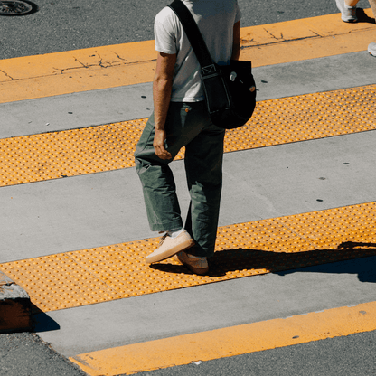 Person walking on a crosswalk wearing beige low-top sneakers.