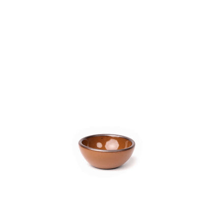A tiny rounded ceramic bowl in a glossy caramel brown color featuring iron speckles and an unglazed rim