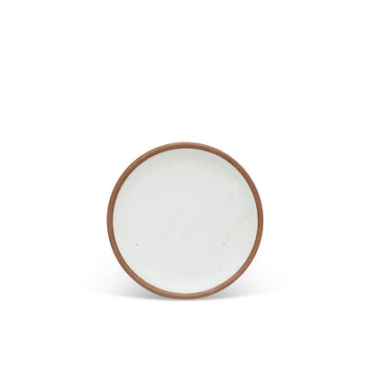 A dessert sized ceramic plate in a cool white color featuring iron speckles and an unglazed rim.