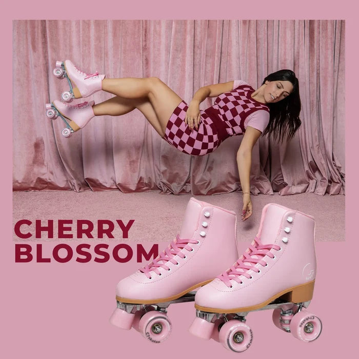 Person wearing pink checkered dress and cherry blossom roller skates against a pink curtain background