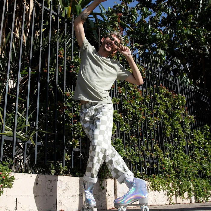 Person wearing checkered pants and colorful roller skates in an outdoor setting with greenery.