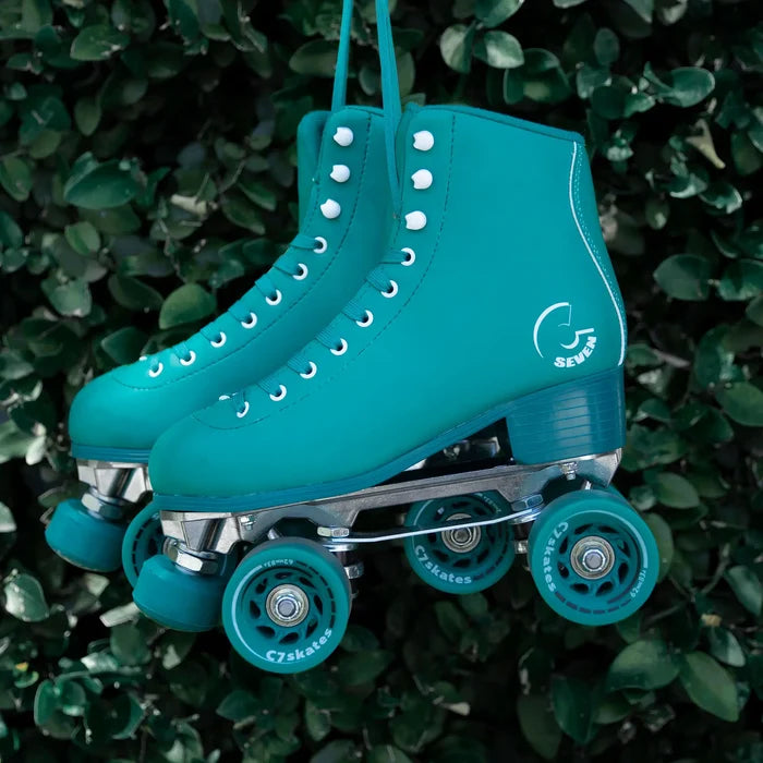Turquoise roller skates with visible brand logo on a green leafy background
