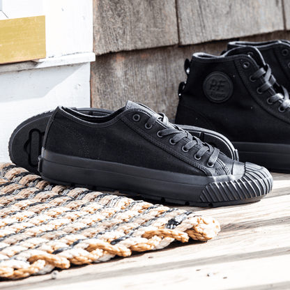 Black low-top sneakers on a wooden porch with a woven mat.