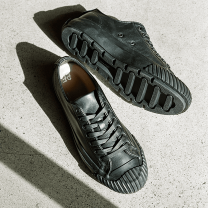 Pair of black leather low-top sneakers on a concrete floor.