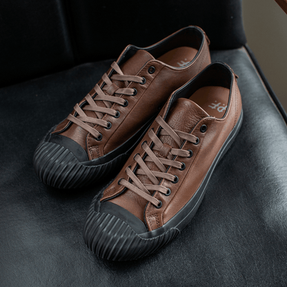 Brown leather low-top sneakers on a chair.
