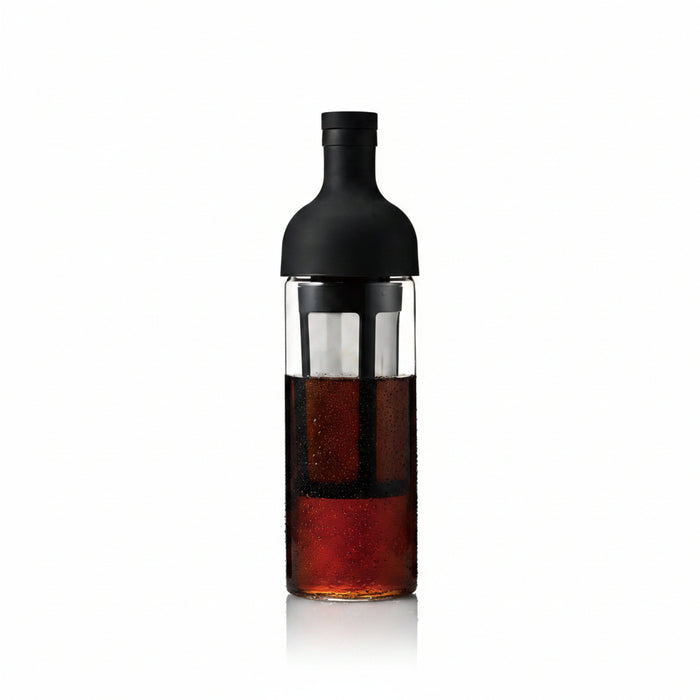 Bottle with a black cap and clear body containing a dark liquid on a white background