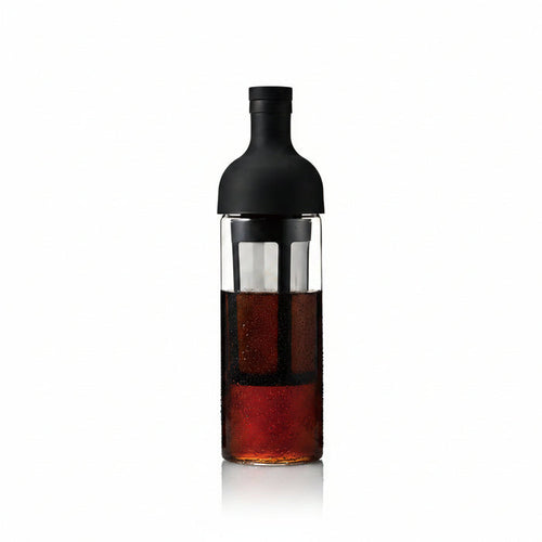 Bottle with a black cap and clear body containing a dark liquid on a white background