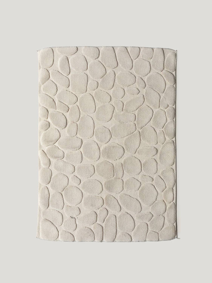 Textured beige bathmat on a light gray background