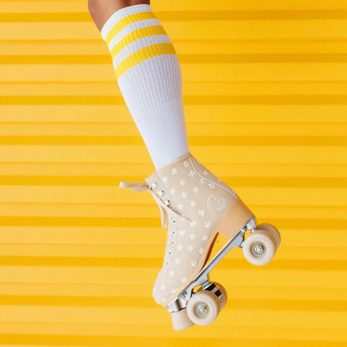 Beige roller skate with white socks and yellow stripes on a yellow background