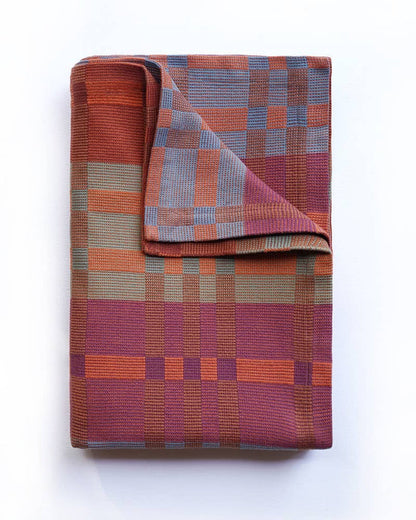 Folded plaid blanket with a geometric pattern on a white background