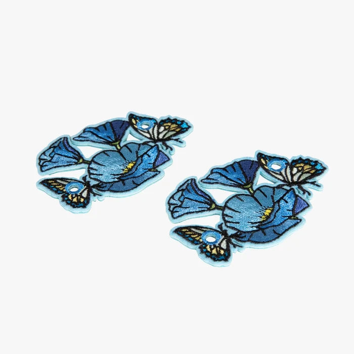 Two blue floral charms with butterflies on a white background