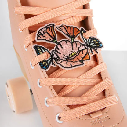 Close-up of a pink sneaker with floral charm and matching laces on a light background