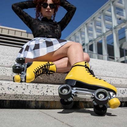 Person wearing yellow roller skates sitting on steps with a modern building in the background