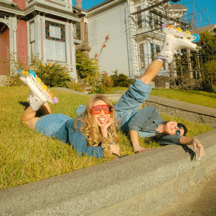 Two people lying on grass with nerf guns in front of a house