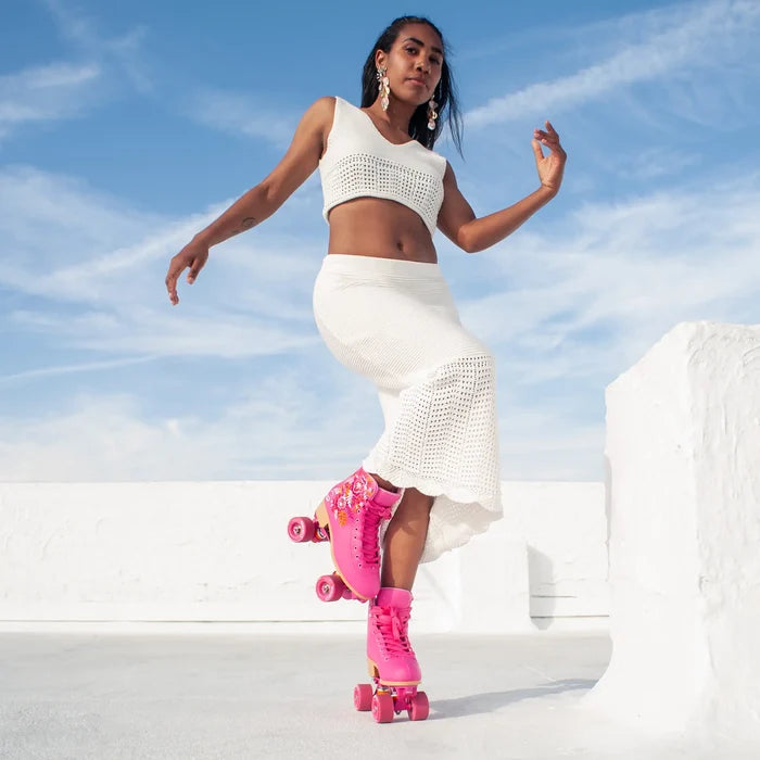 Woman in white outfit with pink roller skates against a blue sky