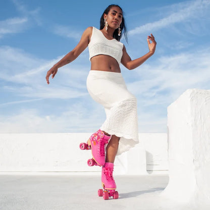 Woman in white outfit with pink roller skates against a blue sky