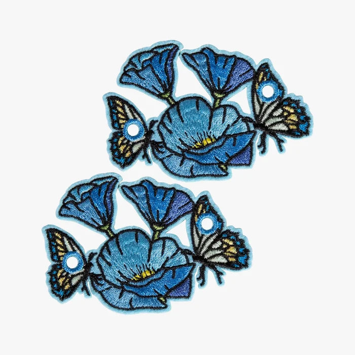 Embroidered patches of blue flowers and butterflies on a white background