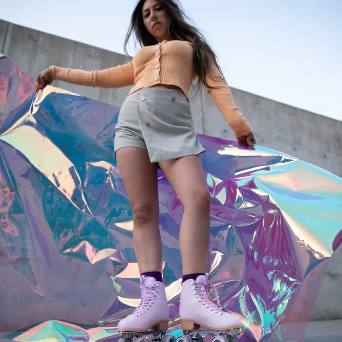 Woman in a peach cardigan and light gray skirt standing on a reflective, iridescent surface.